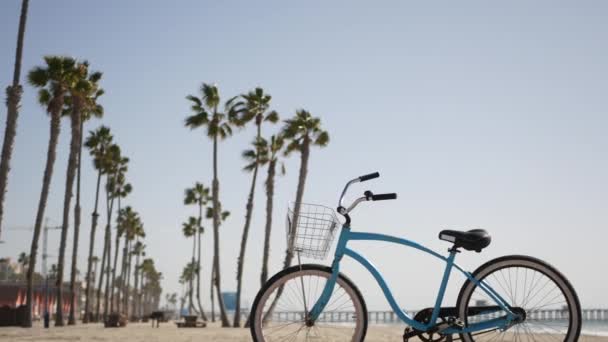 Bicicleta de crucero en bicicleta por la playa del océano, costa de California EE.UU.. Ciclo de verano, cabaña salvavidas y palmera — Vídeo de stock