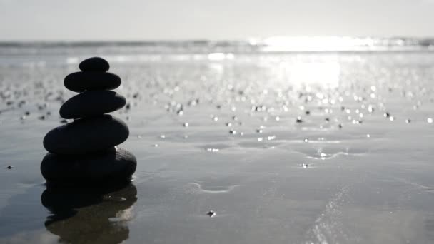 Balanceo de rocas en la playa oceánica, piedras apiladas por olas de agua de mar. Pirámide de guijarros en la orilla arenosa — Vídeos de Stock