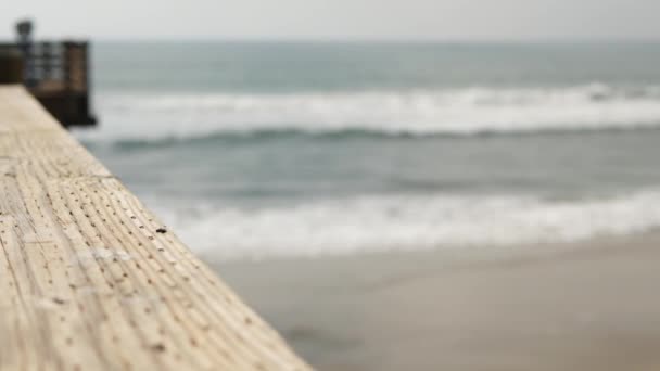 Räcke av träbrygga, strandpromenad, Kaliforniens strand USA. Oskärpa hav, havsvågor. — Stockvideo