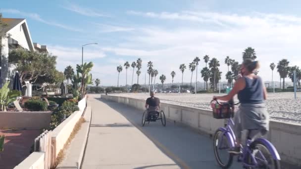 美国加利福尼亚州圣地亚哥 2020年11月19日 海滨人行道上的人们骑自行车 在太平洋海滩上进行体育娱乐活动 骑自行车的人在任务海滩海滨路线上骑车 海岸度假 — 图库视频影像