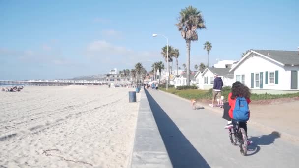 San Diego, Kalifornie USA - 25. listopadu 2020: Lidé na plážové lávce jezdí na kolech, sportovní rekreace na pláži Pacifického oceánu. Cyklisté na plážové trase Mission Waterfront. Dovolená na pobřeží.