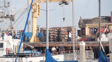 Monterey, California USA - 9 Aralık 2020: Cannery Row yakınlarındaki balıkçı iskelesi. Limandaki iskelede balıkçılık işçileri gemiyle rıhtımda, Amerika 'da balıkçılık. Balık yemi tuzağı ya da ağ kafesi olan adamlar..