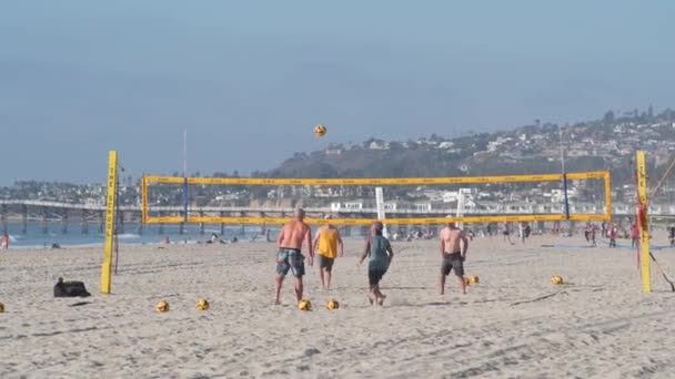 圣地亚哥 加利福尼亚州 2020年11月25日 在海滩球场打排球的球员 用球和网打排球的人 人们在沙滩上的海岸 任务海滩前散步 海岸运动场上的男子 — 图库视频影像