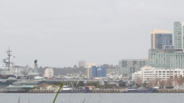 San Diego, California USA - 27 Aralık 2020: Şehir merkezindeki şehir merkezi. Limandaki yüksek gökdelenler. USS Midway donanma gemisi, savaş gemisi, savaş gemisi veya askeri filo gemisi, silahlı kuvvetler. Uçak iniyor..