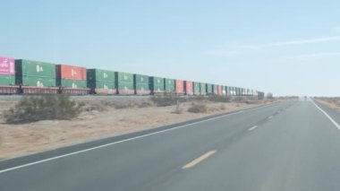 Niland, California, ABD - 22 Aralık 2020: Solton Denizi kıyısındaki çölde uzun endüstriyel tren, demiryolu veya demiryolu üzerindeki kargo metal konteynerleri. Lojistik ulaşım, demiryolunda ticari tren seti..