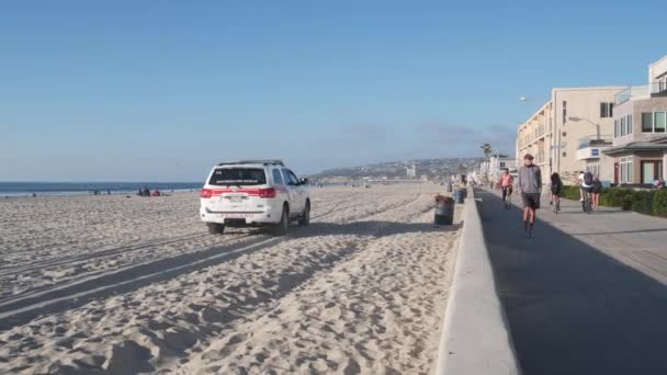 カリフォルニア州サンディエゴ 2020年11月25日 ライフガードホワイトピックアップトラック ミッションビーチのライフガードオート 救助は海の海岸で車を拾う サーフィンや公共の安全 ライフセーバー911車や人々 — ストック動画