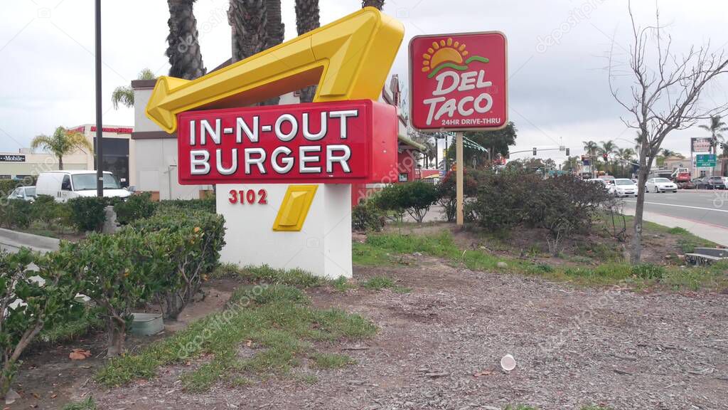 San Diego, California USA - 24 Dec 2020: Fast food restaurants on city street. In-n-out Burger drive thru, Del Taco logo, marketing advertising signs by road or highway. American brands, advertisement