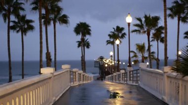 Yağmur damlaları, Oceanside California USA 'da akşam. İskele, alacakaranlıkta avuçlar. Işığın yansıması.