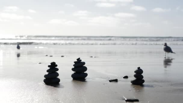 Roccia che si equilibra sulla spiaggia dell'oceano, pietre impilate dalle onde dell'acqua di mare. Piramide di ciottoli sulla riva sabbiosa — Video Stock