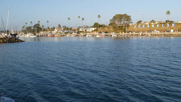 Sunset kilátás tengervíz vitorlás hajó vagy jacht, Oceanside kikötő, nyári vakáció Kalifornia USA. Városi jel a kikötőben, szöveges levelek a kikötőben. Csendes-óceáni part, bálna figyelés túra. — Stock Fotó
