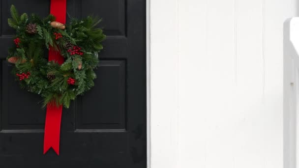 Grüner Weihnachtskranz aus Kiefer oder Tanne und rotes Band an der Tür, Silvesterdekor. — Stockvideo