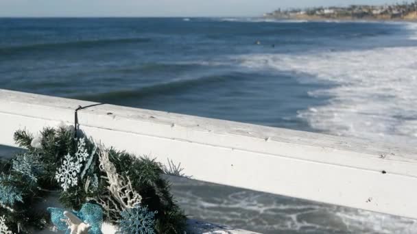 Kerstkrans op pier, Nieuwjaar aan de oceaankust, Californië strand op Xmas. — Stockvideo