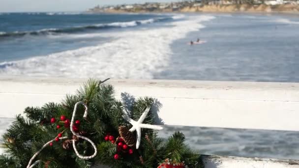 Kerstkrans op pier, Nieuwjaar aan de oceaankust, Californië strand op Xmas. — Stockvideo