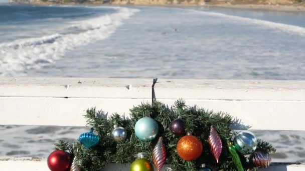 Corona de Navidad en el muelle, Año Nuevo en la costa del océano, playa de California en Navidad. — Vídeos de Stock