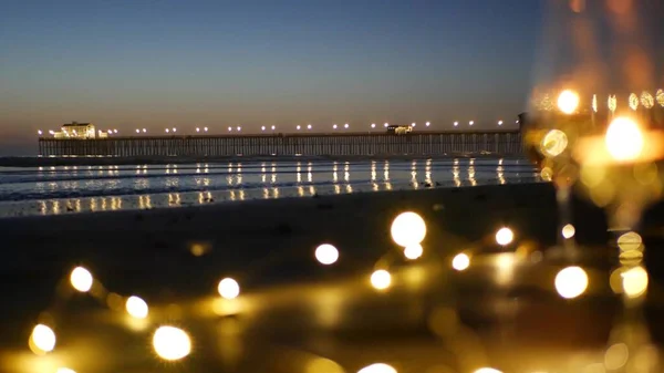 Luces de llama de vela en vidrio, fecha romántica playa por las olas del océano, mar de verano. Luz de las velas en la arena. — Foto de Stock