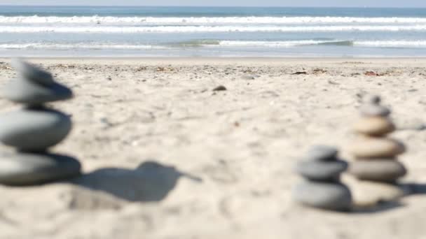 바다의 해변에서 바위가 균형을 이루고, 파도에 밀려 쌓이는 돌들. 모래사장에 있는 자갈들의 피라미드 — 비디오