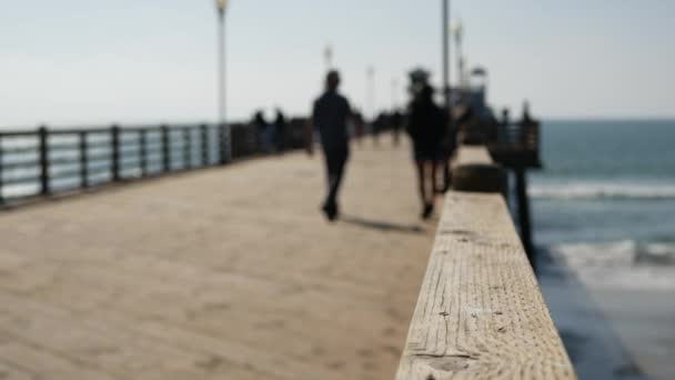 Wooden pier waterfront boardwalk, California beach USA. Defocused ocean, sea waves. People walking. — Stock Video