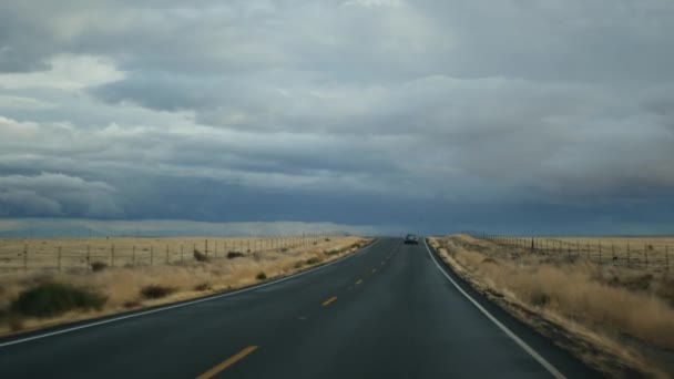开车，在美国加州的公路旅行，从汽车上看。搭便车在美国旅行。暴雨前的公路、高山和多云的天空.美国风景大道。乘客POV — 图库视频影像