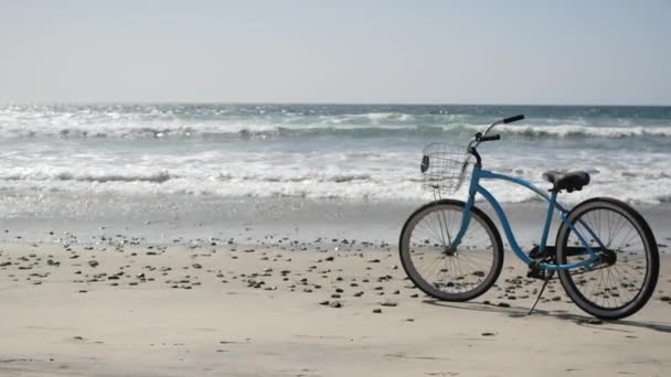 Cykel cruiser cykel vid havet stranden Kalifornien kust USA. Sommartid blå cykel, sand och vatten våg — Stockvideo