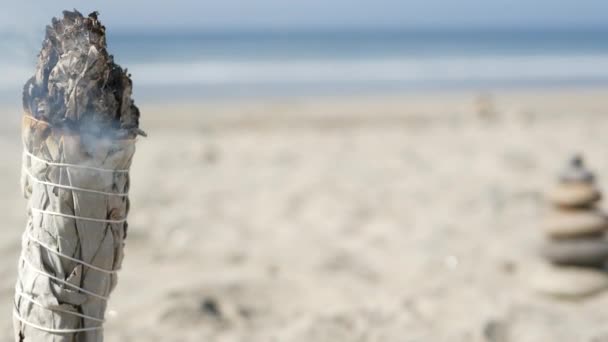 Humo de salvia blanca, quemadura de palo de mancha. Meditación de manchas de aroma en la playa del océano, olas de agua de mar. — Vídeos de Stock