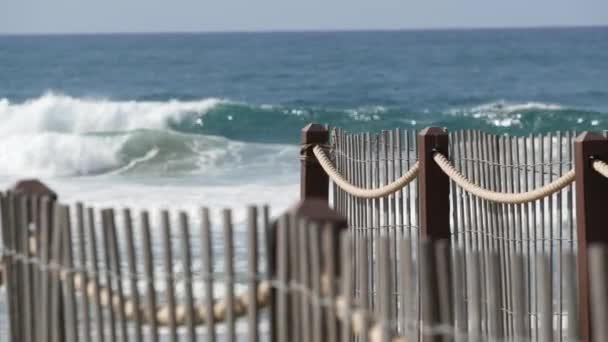 Letní vlny na pláži, Kalifornské pobřeží USA. Pobřeží Tichého oceánu, laťkový plot na pobřeží.