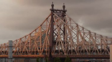 Queens, Queensboro Köprüsü mimarisinden New York City Manhattan şehir merkezi silueti. Çatıdan şehir manzarası, Long Island Hunters Point. Ulaşım köprüsünün üzerinde gün batımı. Yağmurlu bulutlar.