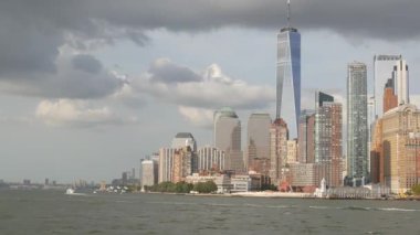 New York City Manhattan şehir merkezi feribottan Özgürlük Adası 'na, Amerika Birleşik Devletleri' ne ufuk çizgisi. Finans Bölgesi şehir manzarası, Dünya Ticaret Merkezi gökdelen kulesi. Şehir binaları mimarisi. Yağmur bulutları.
