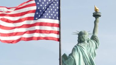 Özgürlük Heykeli Özgürlük Adası, New York, ABD 'de. Arkadan Cooper anıtı, New York, Manhattan yakınlarında demokrasi ve vatanseverlik sembolü. Rüzgarda dalgalanan Amerikan bayrağı. Bağımsızlık kavramı.
