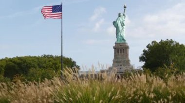Özgürlük Heykeli Özgürlük Adası, New York, ABD 'de. Arkadan Cooper anıtı, New York, Manhattan yakınlarında demokrasi ve vatanseverlik sembolü. Rüzgarda dalgalanan Amerikan bayrağı. Bağımsızlık kavramı.