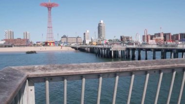 Coney Adası plajı, Brooklyn, New York, ABD 'de ahşap iskele geçidi. Retro Ay Parkı 'nın yanındaki sahil yolunda. Okyanus kıyısındaki eğlence parkı. NYC, ABD 'de yaz tatilindeki insanlar.