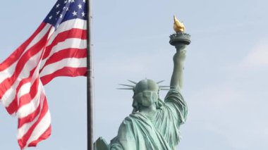 Özgürlük Heykeli Özgürlük Adası, New York, ABD 'de. Arkadan Cooper anıtı, New York, Manhattan yakınlarında demokrasi ve vatanseverlik sembolü. Rüzgarda dalgalanan Amerikan bayrağı. Bağımsızlık kavramı.