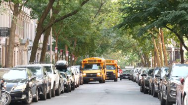 New York, ABD - 15 Eylül 2024: Kentsel yerleşim binaları, Manhattan klasik caddesi. Yukarı Batı Yakası, New York 'taki tipik evler. Sonbahar ağaçlarının altında sarı okul servisi..