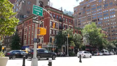 New York, ABD - 9 Eylül 2024: Manhattan Midtown Caddesi, Chelsea. Kırmızı tuğlalı ev yerleşim bölgesi mimarisi. İnsanlar yaya, kavşaktaki sarı taksi arabası. Lincoln Tüneli işareti