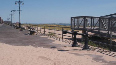 Brooklyn, New York, ABD 'deki Coney Adası plaj gezisi. Retro Ay Parkı 'nın yakınındaki tahta tahta kaldırım. Okyanus kıyısındaki banklar, kumlu sahil. NYC, ABD 'de liman tatili. Açık hava eğlencesi