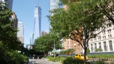 Aşağı Manhattan Finansal Bölgesi, New York, ABD. Bir Dünya Ticaret Merkezi gökdelen binası, Battery Park 'tan Özgürlük Kulesi. Yaz ağaçları yeşillik, Batı sokağı perspektifi.