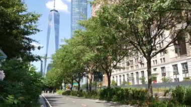 Aşağı Manhattan Finansal Bölgesi, New York, ABD. Bir Dünya Ticaret Merkezi gökdelen binası, Battery Park 'tan Özgürlük Kulesi. Yaz ağaçları yeşillik, Batı sokağı perspektifi.