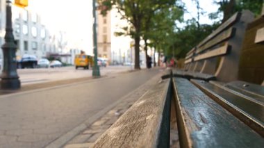 New York 'taki Central Park yakınlarında ahşap bank, Birleşik Devletler. Arabalar ve insanlar Manhattan, ABD 'de sokakta. Odaklanmamış perspektif. Sarı taksi yolda..