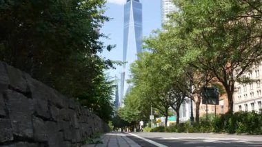 Aşağı Manhattan Finansal Bölgesi, New York, ABD. Bir Dünya Ticaret Merkezi gökdelen binası, Battery Park 'tan Özgürlük Kulesi. Yaz ağaçları yeşillik, Batı sokağı perspektifi.