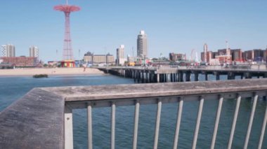 Coney Adası plajı, Brooklyn, New York, ABD 'de ahşap iskele geçidi. Retro Ay Parkı 'nın yanındaki sahil yolunda. Okyanus kıyısındaki eğlence parkı. NYC, ABD 'de yaz tatilindeki insanlar.