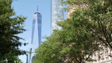 Aşağı Manhattan Finansal Bölgesi, New York, ABD. Bir Dünya Ticaret Merkezi gökdelen binası, Battery Park 'tan Özgürlük Kulesi. Yaz ağaçları yeşillik, Batı sokağı perspektifi.