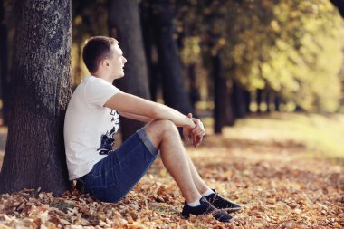 Sonbahar parkta oturan genç adam