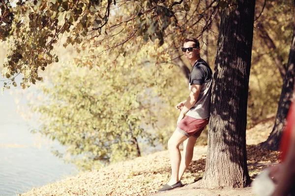 Jovem sentado no parque de outono — Fotografia de Stock