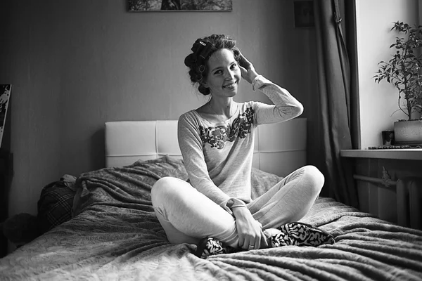 Hübsche Hausfrau sitzt auf Bett — Stockfoto