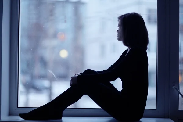 Mädchen sitzt am Fenster — Stockfoto