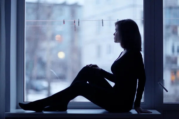 Menina sentada perto da janela — Fotografia de Stock