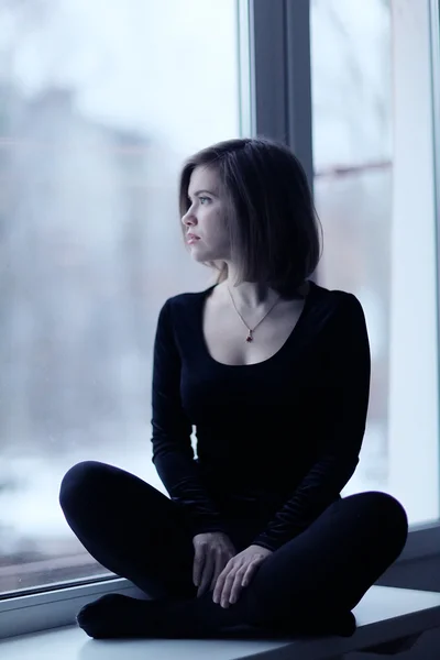 Menina sentada perto da janela — Fotografia de Stock