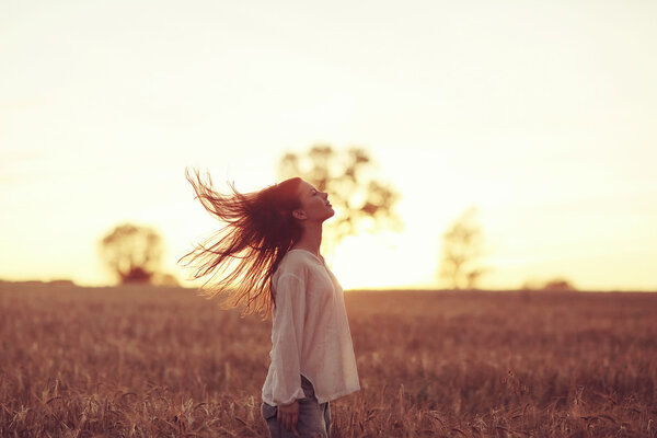 Girl with long hair at sunset in the field