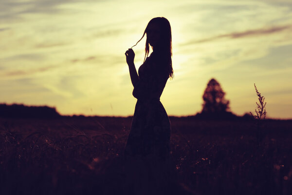 Girl in the field on sky background at sunset