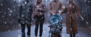 Parkta kış yürüyüşü, küçük bir çocuk ve arkadaşlarıyla genç bir aile, genç ebeveynler mevsim dışında.