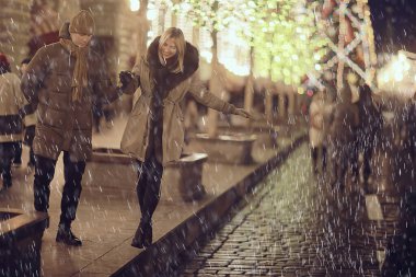 Birbirine aşık çiftler, yılbaşı yürüyüşünde şehirde akşam karları, aralık ayında yeni yıl tatili.